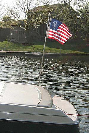 US Yacht Ensign Nylon Embroidered and Sewn Flag 16 x 24 flying on a boat, showing its detailed embroidered stars and sewn strips.