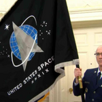 A man in uniform holds the US Space Force Government Issue Indoor Flag, 3' x 5' with silver fringe and brass grommets.