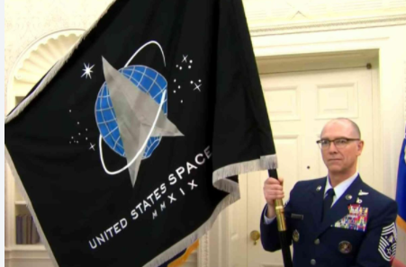 A man in uniform holds the US Space Force Government Issue Indoor Flag, 3' x 5' with silver fringe and brass grommets.