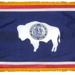 Wyoming State Flag 4' x 6' INDOOR Printed Nylon, featuring a buffalo symbol on a blue and white seal, with a flannel-lined pole sleeve and rayon fringe.